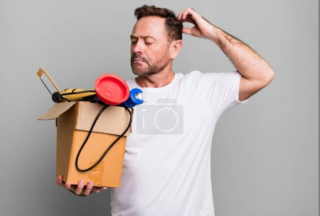 Foto de Hombre de mediana edad sintiéndose desconcertado y confundido, rascándose la cabeza. manitas con caja de herramientas - Imagen libre de derechos