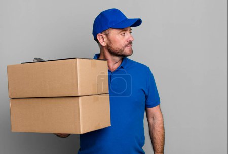 Photo for Middle age man on profile view thinking, imagining or daydreaming. paker delivery man. packer delivery man - Royalty Free Image