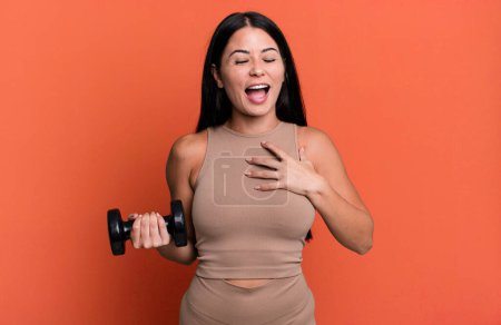 Photo for Hispanic pretty woman laughing out loud at some hilarious joke. fitness concept and dumbbell - Royalty Free Image
