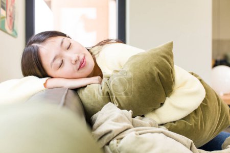Téléchargez les photos : Asiatique jolie femme avec un oreiller et reposant sur un canapé - en image libre de droit
