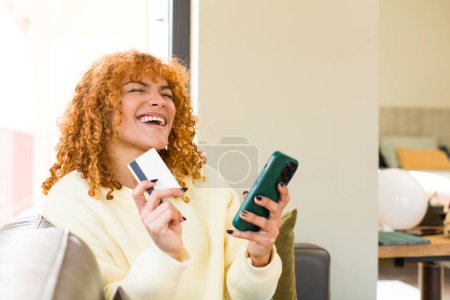 Foto de Young red hair latin pretty woman using a smartphone at home - Imagen libre de derechos