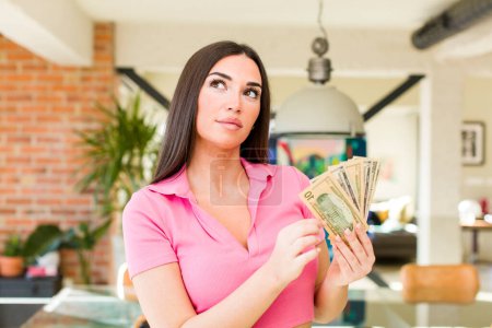 Photo for Pretty young woman with dollarbanknotes at home interior - Royalty Free Image