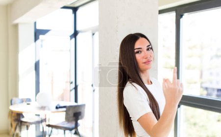 Téléchargez les photos : Young adult pretty woman feeling angry, annoyed, rebellious and aggressive, flipping the middle finger, fighting back - en image libre de droit
