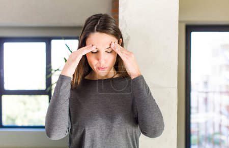 Photo for Young adult pretty woman looking stressed and frustrated, working under pressure with a headache and troubled with problems - Royalty Free Image