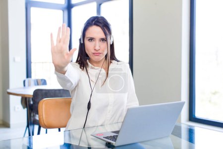 Photo for Young pretty woman looking serious showing open palm making stop gesture. telemarketer concept - Royalty Free Image