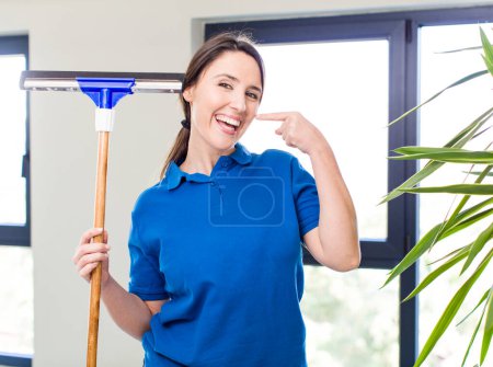 Photo for Young pretty woman smiling confidently pointing to own broad smile. windows washer concept - Royalty Free Image