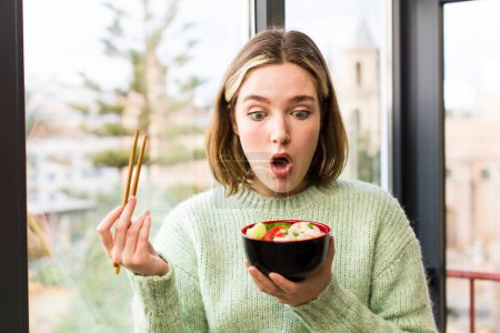 Téléchargez les photos : Jolie jeune femme mangeant un bol de nouilles chinoises ramen. design intérieur de la maison - en image libre de droit
