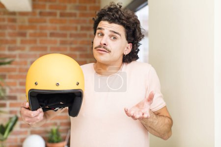 Photo for Young handsome man holding a motorbike helmet at home interior - Royalty Free Image