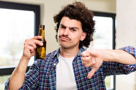 Téléchargez les photos : Jeune homme beau avec une bière à la maison à l'intérieur de la maison - en image libre de droit