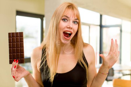 Téléchargez les photos : Jeune jolie femme avec une barre de chocolat à l'intérieur de la maison - en image libre de droit