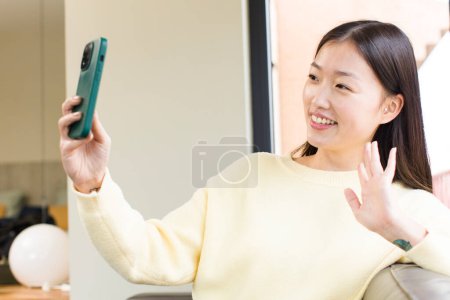Téléchargez les photos : Asian pretty woman using a smartphone  at home - en image libre de droit