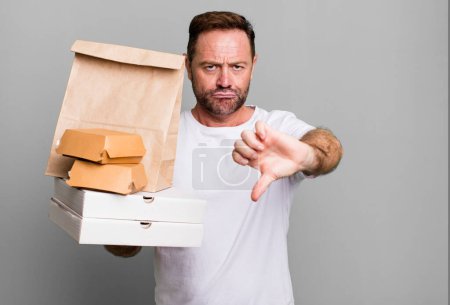 Foto de Hombre de mediana edad sintiendo cruz, mostrando los pulgares hacia abajo. entrega y comida rápida para llevar concepto - Imagen libre de derechos