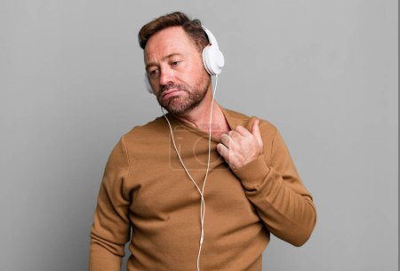 Téléchargez les photos : Homme d'âge moyen se sentant stressé, anxieux, fatigué et frustré. écouter de la musique avec un casque - en image libre de droit