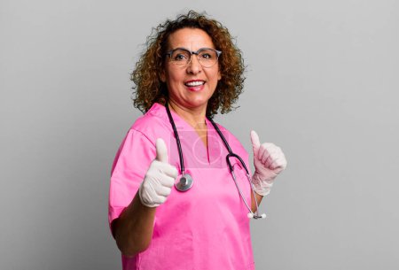 Photo for Pretty middle age woman feeling proud,smiling positively with thumbs up. nurse concept - Royalty Free Image