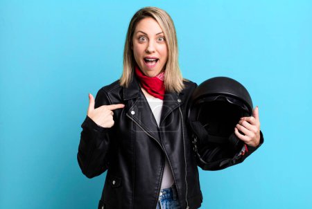 Photo for Pretty blonde woman feeling happy and pointing to self with an excited. motorbike rider and helmet concept - Royalty Free Image