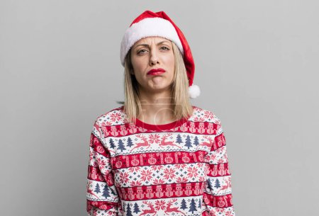 Téléchargez les photos : Pretty blonde woman feeling sad and whiney with an unhappy look and crying. christmas and santa hat concept - en image libre de droit