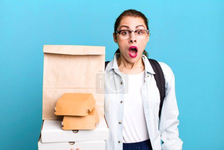 Photo for Pretty hispanic woman looking very shocked or surprised. delivery fast food take away concept - Royalty Free Image