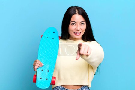 Téléchargez les photos : Hispanique jolie femme pointant vers la caméra vous choisissant. concept de skate board - en image libre de droit