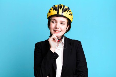 Foto de Joven mujer bonita sonriendo con una expresión feliz y segura con la mano en la barbilla. concepto de bicicleta y mujer de negocios - Imagen libre de derechos