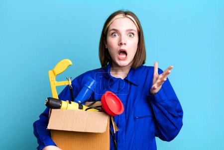 Photo for Young pretty woman feeling extremely shocked and surprised. housekeeper and toolbox concept - Royalty Free Image