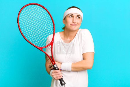 Foto de Joven bonita mujer encogiéndose de hombros, sintiéndose confundida e incierta. concepto de tenis - Imagen libre de derechos