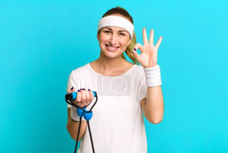 Foto de Joven bonita mujer sintiéndose feliz, mostrando aprobación con buen gesto. concepto de fitness - Imagen libre de derechos