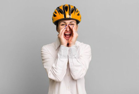 Photo for Young pretty woman feeling happy,giving a big shout out with hands next to mouth. business and bike concept - Royalty Free Image