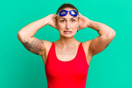 Photo for Young pretty woman feeling stressed, anxious or scared, with hands on head. swimmer concept - Royalty Free Image