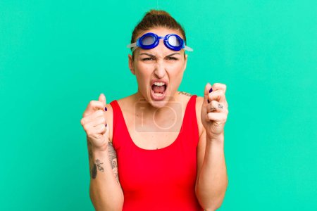 Photo for Young pretty woman shouting aggressively with an angry expression. swimmer concept - Royalty Free Image
