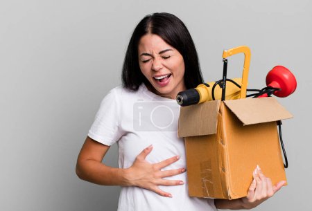 Foto de Mujer bonita hispana riendo en voz alta en alguna broma hilarante con una caja de herramientas - Imagen libre de derechos