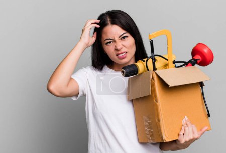 Photo for Hispanic pretty woman feeling confused and puzzled, showing you are insane with a tool box - Royalty Free Image