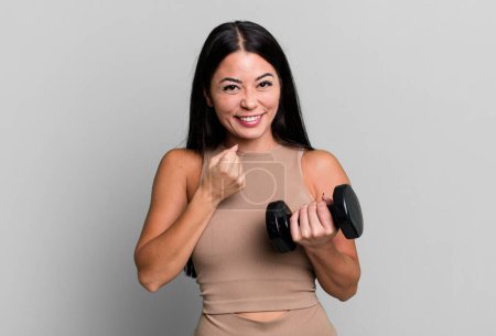 Photo for Hispanic pretty woman feeling happy and facing a challenge or celebrating. fitness concept and dumbbell - Royalty Free Image