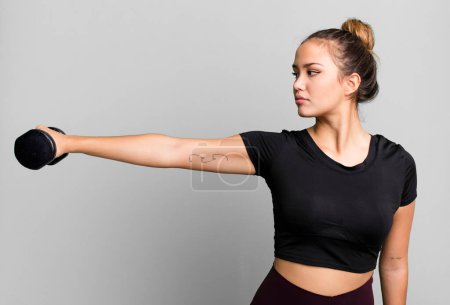 Foto de Hispanic pretty young woman lifting a dumbbell. fitness concept - Imagen libre de derechos