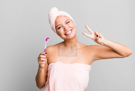 Photo for Hispanic pretty young woman wearing bathrobe ang a teeth brush - Royalty Free Image
