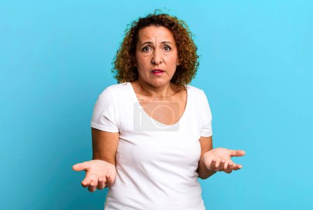 Photo for Middle age hispanic woman feeling clueless and confused, not sure which choice or option to pick, wondering - Royalty Free Image