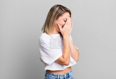 Photo for Blonde adult woman covering eyes with hands with a sad, frustrated look of despair, crying, side view - Royalty Free Image