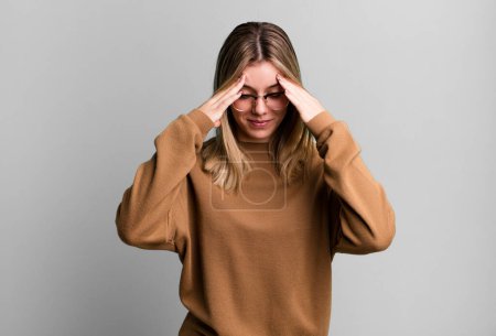 Foto de Rubia bonita mujer buscando estresado y frustrado, trabajando bajo presión con un dolor de cabeza y con problemas - Imagen libre de derechos