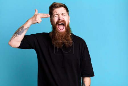 Téléchargez les photos : Barbe longue et cheveux roux homme regardant malheureux et stressé, geste suicidaire faisant signe d'arme à feu - en image libre de droit
