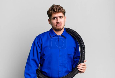 Photo for Young adult caucasian man feeling sad and whiney with an unhappy look and crying. bike repairman or mechanic concept - Royalty Free Image