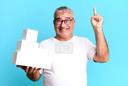 Téléchargez les photos : Homme âgé d'âge moyen se sentant comme un génie heureux et excité après avoir réalisé une idée. différents paquets boîtes vides - en image libre de droit