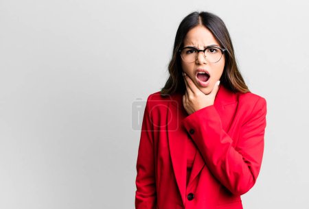 Photo for Hispanic pretty woman with mouth and eyes wide open and hand on chin. businesswoman concept - Royalty Free Image