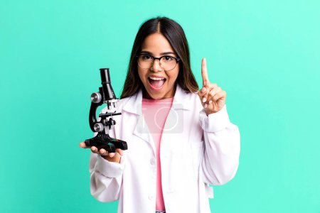 Photo for Hispanic pretty woman feeling like a happy and excited genius after realizing an idea. scients student with a microscope - Royalty Free Image