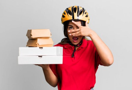Photo for Hispanic pretty woman looking shocked, scared or terrified, covering face with hand.  delivery woman and take away concept - Royalty Free Image