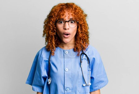 Photo for Red hair pretty woman looking very shocked or surprised. nurse concept - Royalty Free Image