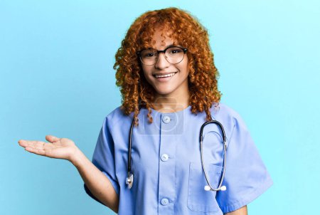 Téléchargez les photos : Cheveux roux jolie femme souriant joyeusement, se sentant heureux et montrant un concept. concept d'infirmière - en image libre de droit