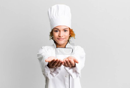 Photo for Red hair pretty woman smiling happily with friendly and  offering and showing a concept. chef concept - Royalty Free Image