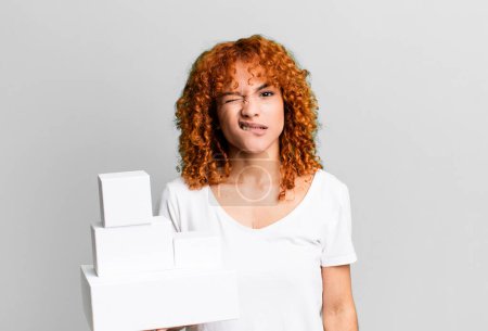 Téléchargez les photos : Cheveux roux jolie femme regardant perplexe et confus. concept de boîtes de paquets vides - en image libre de droit