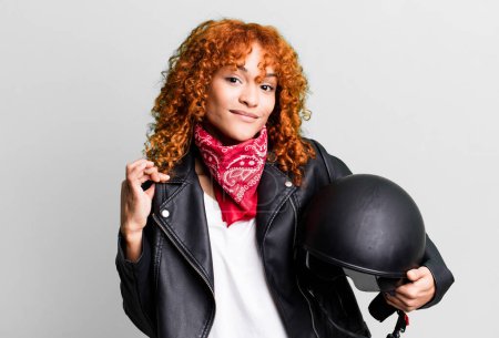 Téléchargez les photos : Cheveux roux jolie femme à l'air arrogant, réussi, positif et fier. concept de motocycliste - en image libre de droit