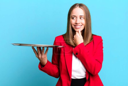 Photo for Smiling with a happy, confident expression with hand on chin. businesswoman presenting with a tray - Royalty Free Image