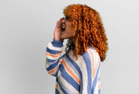 Photo for Redhair pretty woman profile view, looking happy and excited, shouting and calling to copy space on the side - Royalty Free Image
